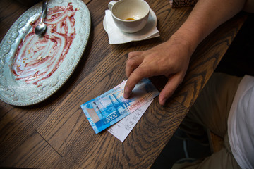 Fototapeta na wymiar New 2000 rubles banknote in mans hand in cafe.