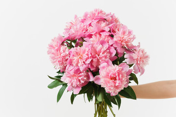 Female hand holding beautiful bouquet of pink peonies flowers isolated on white background. St. Valentine's Day, International Women's Day holiday concept. Advertising area copy space to advertisement