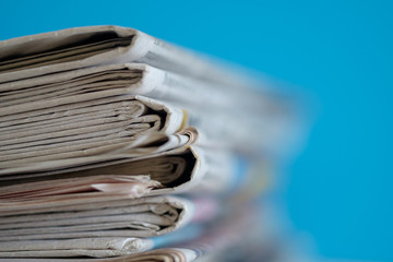 Newspapers folded and stacked with blue background, selective focus.