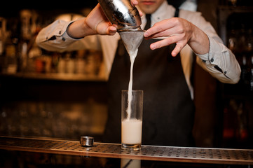 Bartender adding an alcoholic drink from the steel shaker