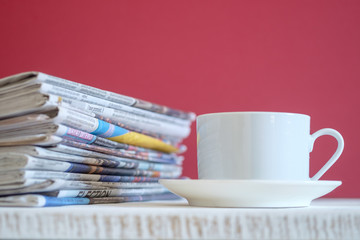 Newspapers folded and stacked with red background, selective focus.