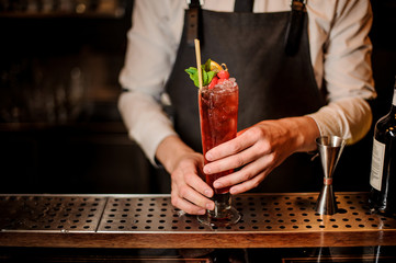 Bartender serving a delicious red summer cocktail