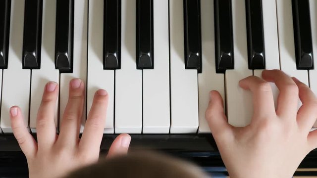 Cute little boy practicing a black upright piano at home