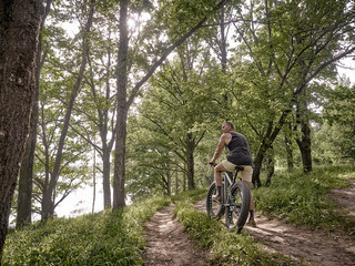 A trained man is riding a fat bike along forest paths.