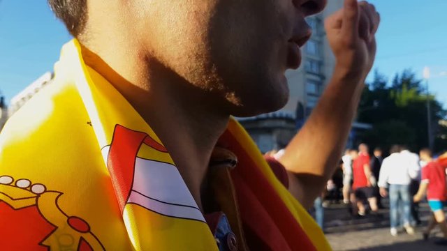 Fan wrapped in Spanish flag shouting Ole, celebrating victory of national team