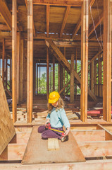 Fototapeta premium child in a helmet on the construction site of a wooden house