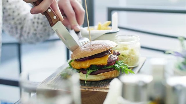 Unrecognizable man cutting a hamburger