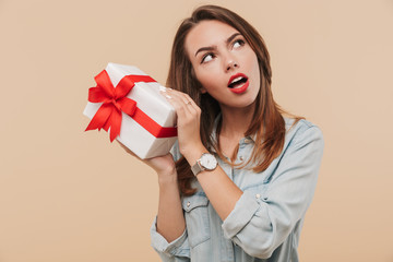 Portrait of a wondering young girl holding present box