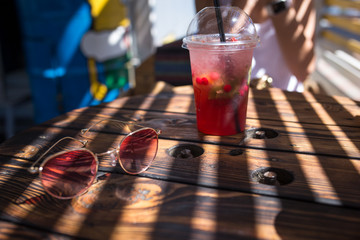 Refreshing cocktail on a wooden table with sunglasses