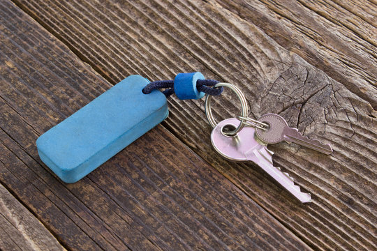 Keys with blue tag on wooden background