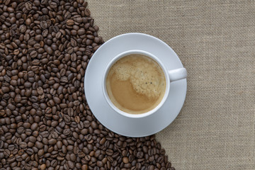 taza de cafe sobre granos de cafe y arpillera vieja