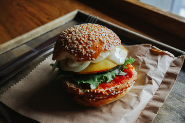 Burger with meat. Homemade cheese burger or hamburger on a wood plate served to put on wood table with copy space. Fast food for breakfast or lunch.