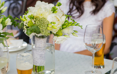 bouquet of the bride in a glass on the wedding table