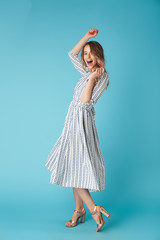 Full length image of Pleased blonde woman in dress dancing