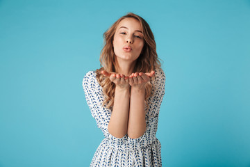 Happy blonde woman in dress sends air kiss