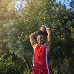 Fototapeta premium Young athlete performs sports exercises with a ball outdoors.