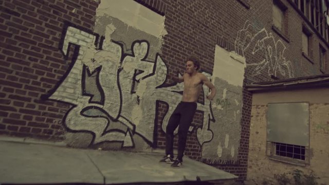 Parkour and Freerunning pro does a huge frontflip drop onto a platform.