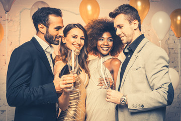 Man, on new year or birthday party opening bottle of champagne together with his friends