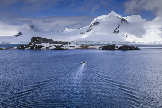 Tourists on a zodiac boat approach Half Moon Island, Livingston Island mountain backdrop, South Shetland Islands, Antarctica