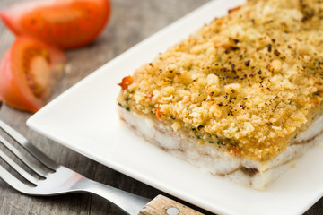 White fish casserole with cheese on wooden background.