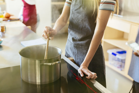 Woman Stirring In Cooking Pot In Kitchen