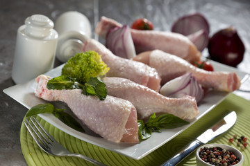 Raw chicken legs with herbs and spices on plate
