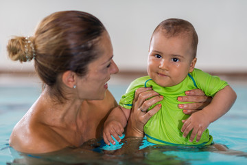 Mother with baby boy in the swimming pool on swimming class