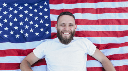 Happy hipster man holding American or USA flag. He is wearing casual clothes.