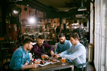 Fototapeta na wymiar Men In Pub Drinking Beer And Eating Food