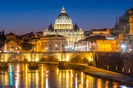 St. Peters Basilica and the Vatican with Ponte St Angelo over river Tiber illuminated at dusk, Rome, Lazio