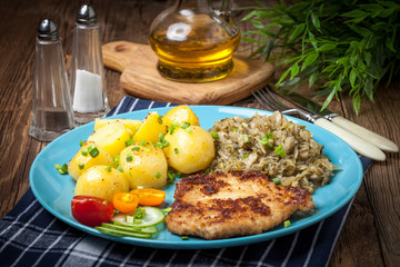 Fried pork chop, baked potatoes and fried young cabbage.