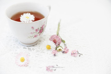 Obraz na płótnie Canvas Cup of tea with daisies on white background