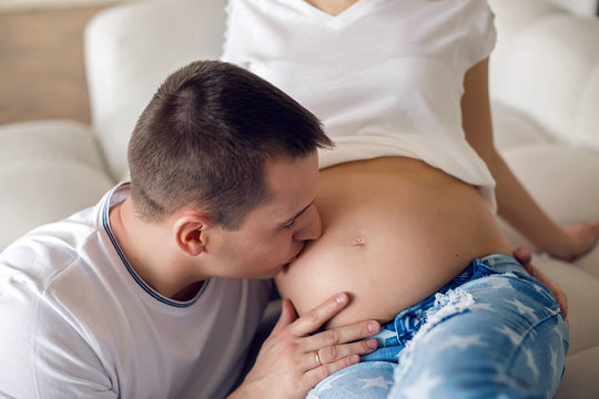 pregnant woman sitting with her husband on the floor next to a white sofa