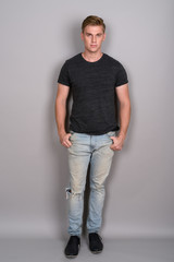 Obraz premium Young handsome man with blond hair wearing gray shirt against gr
