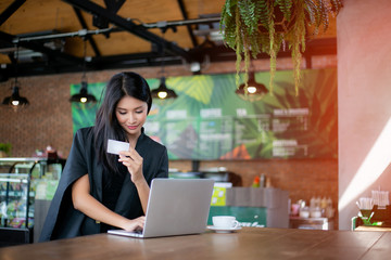 Young woman holding credit card and using laptop computer. Online shopping concept