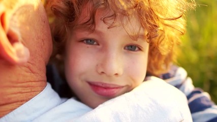 Closeup portrait of a beautiful curly-haired boy who embraces his father. Children's Day. Father's Day