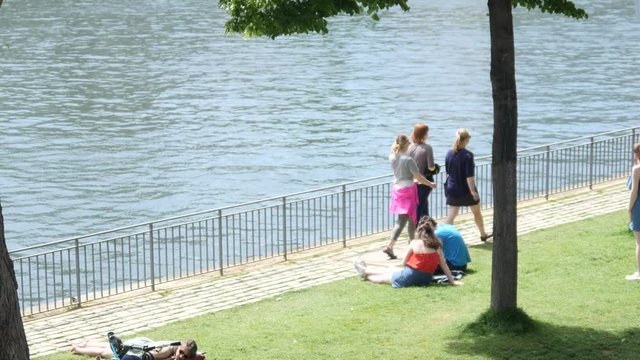 Embankment of Paris river Seine and people walking and rest on a grass lawn