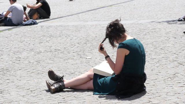 Student girl sit on pedestrian square cobblestone read leaf a book near Pompidou Center in Paris