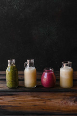 Set of bottles with delicious detox smoothies on rustic wooden board