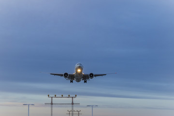 A jetliner  with  headlights on approaches for landing over visual approach slope indicator in a low light
