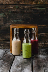 Organic fruit smoothies in glass bottles on wooden background