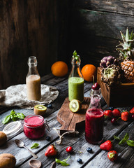 Fresh healthy smoothies in glass bottles on rustic table with assorted fruits