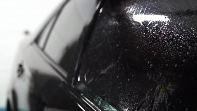 Master installs tint film for car glass with hairdryer and spatula with glare of light. Concept tinting