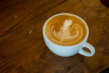 Coffee cup with latte art on wooden background . Selective focus white cup.