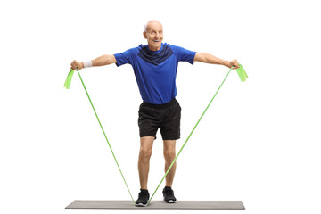 Senior standing on an exercise mat and working out with a rubber band