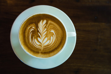 top view of Coffee cup with latte art on wooden table . Selective focus white cup.color vintage style.