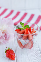 Chia pudding with fresh strawberries and mint in glass on striped background. Concept of healthy breakfast