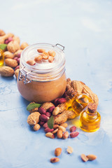 Natural peanut butter with oil in a glass jar and peanuts