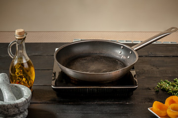 Top view of frying pan with olive oil on wooden table.