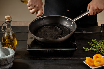 Chef pours olive oil in a pan for making new dish